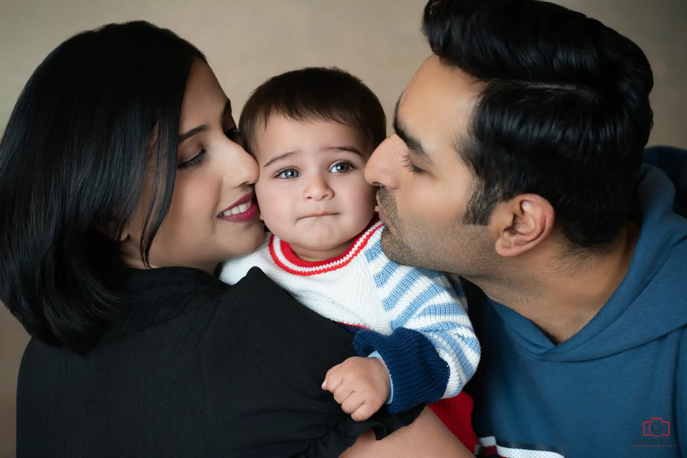 Heartwarming family portrait featuring parents lovingly kissing their baby during a professional family photography session by Ruchika Jain Photography in Wellington